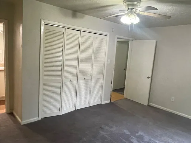 en empty room with closet and a chandelier fan