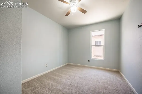 an empty room with a window and a fan