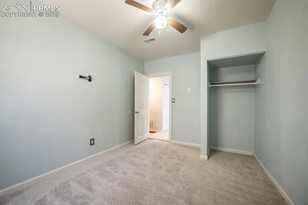 a view of an empty room and a ceiling fan closet