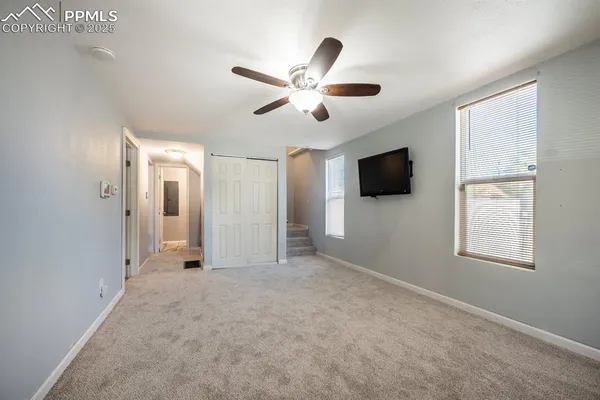 a view of an empty room with window and a ceiling fan