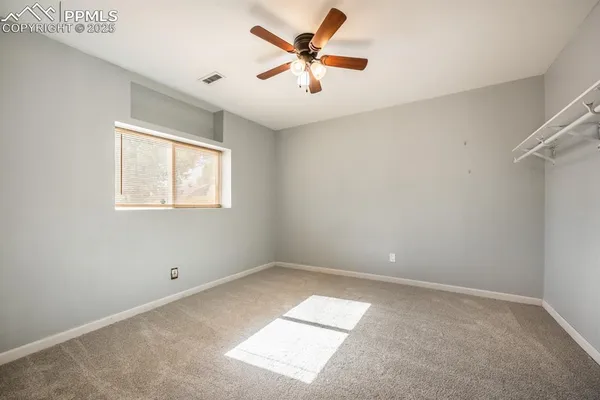 an empty room with ceiling fan and window
