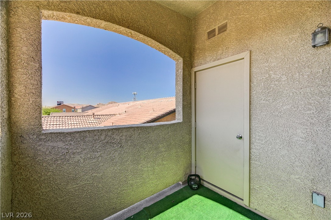 8985 South Durango Drive, Unit 2187 Las Vegas, NV 89113 - Photo 21 of 73 An inviting exterior balcony with an arched opening frames distant rooftops under a clear sky.