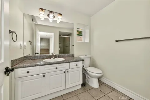 a bathroom with a granite countertop toilet sink and mirror