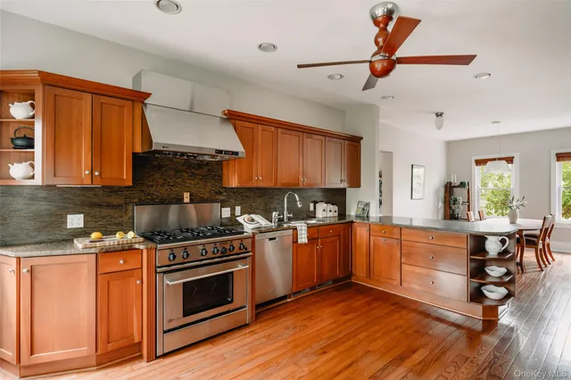 a kitchen with stainless steel appliances granite countertop wooden floors and white cabinets