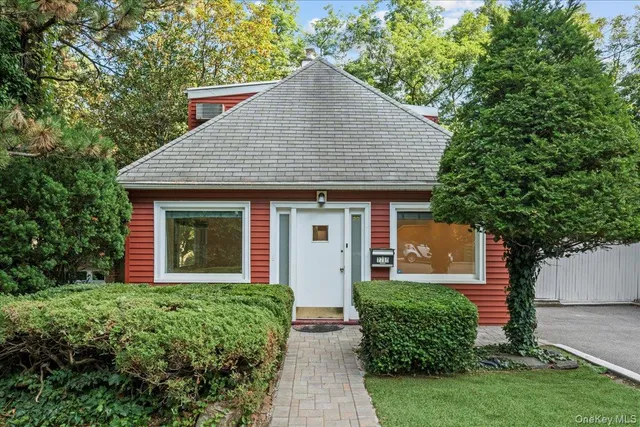 front view of house with a yard and trees all around