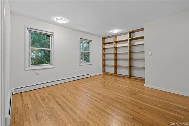 a view of an empty room with a window and wooden floor