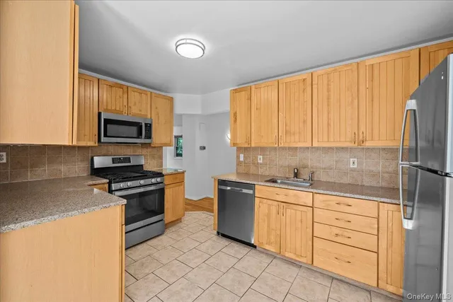 a kitchen with stainless steel appliances granite countertop a stove top oven a sink dishwasher and a refrigerator with wooden cabinets