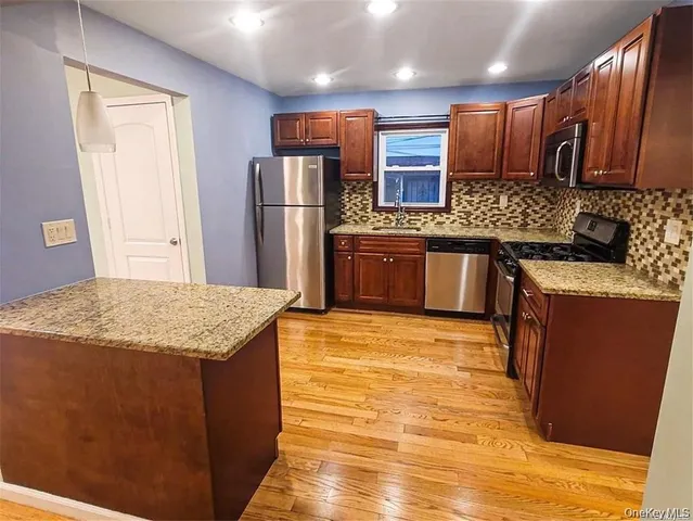 a kitchen with stainless steel appliances granite countertop a sink stove refrigerator and cabinets