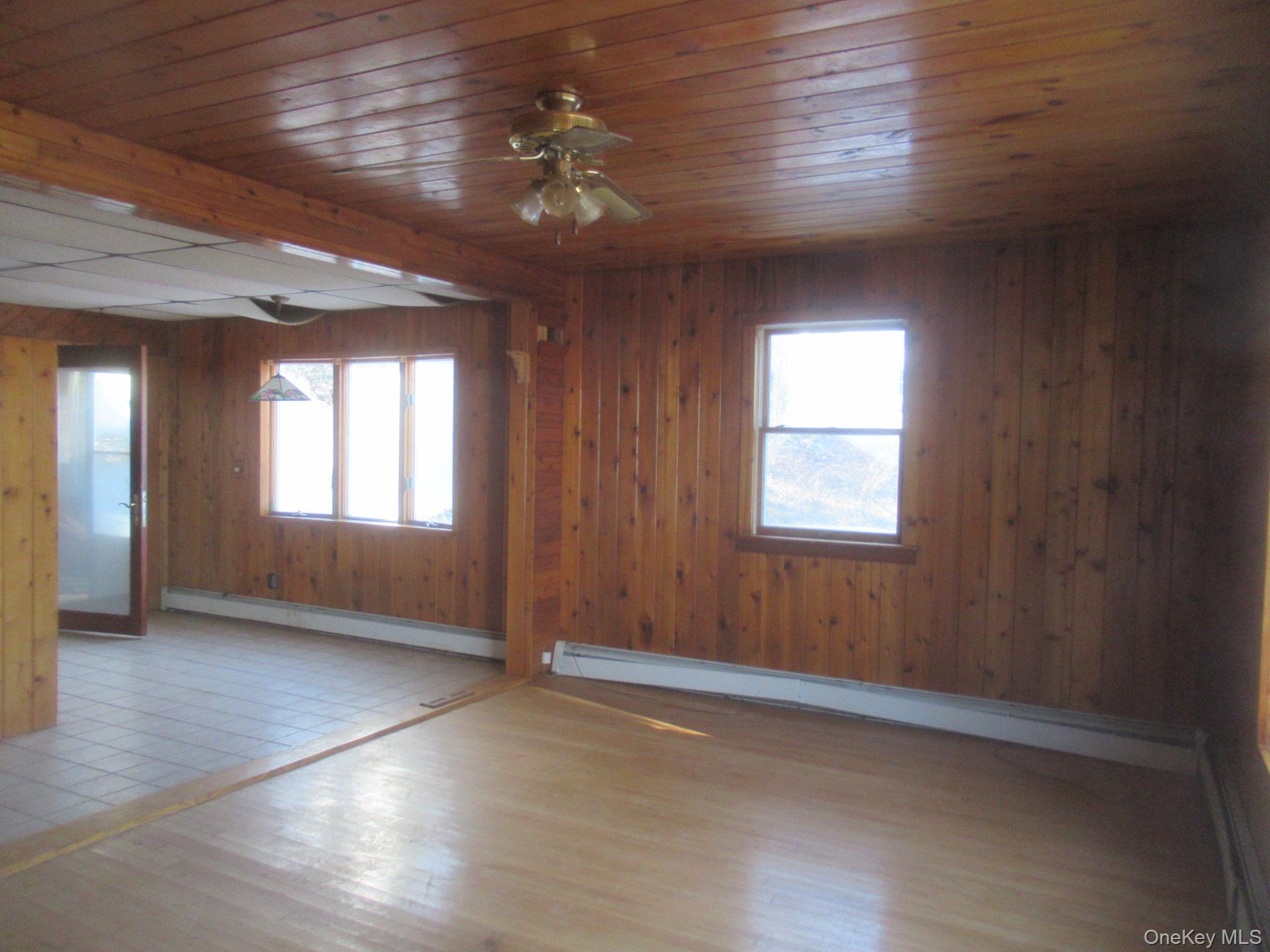 270 Bucks Hollow Road Mahopac, NY 10541 - Photo 7 of 11 Living room featuring wood finished floors, a baseboard radiator, healthy amount of natural light, wood walls, and ceiling fan