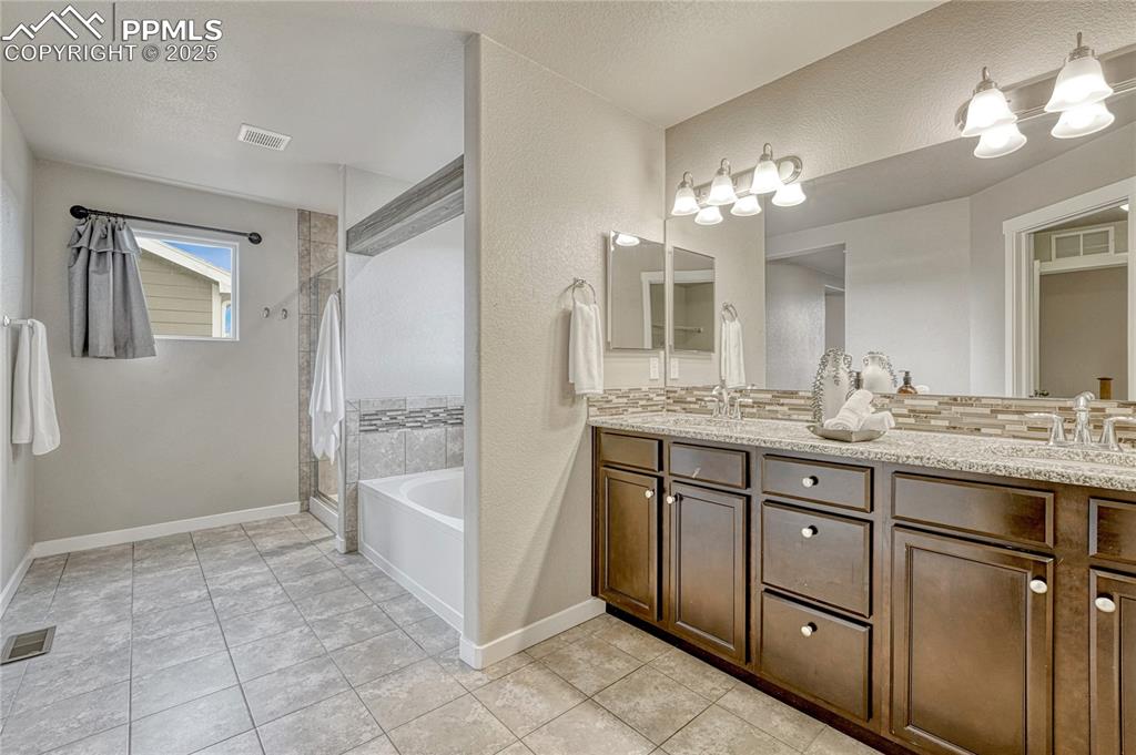 11298 Scenic Brush Drive Peyton, CO 80831 - Photo 22 of 50 a spacious bathroom with a granite countertop sink a toilet a mirror a vanity and shower