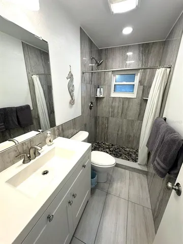 a bathroom with a sink a toilet a mirror and shower