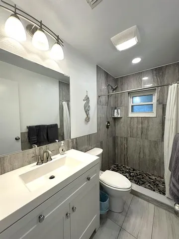 a bathroom with a sink a toilet a mirror and shower