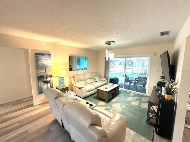 a living room with furniture flat screen tv and a large window