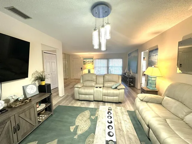 a living room with furniture a flat screen tv and a chandelier