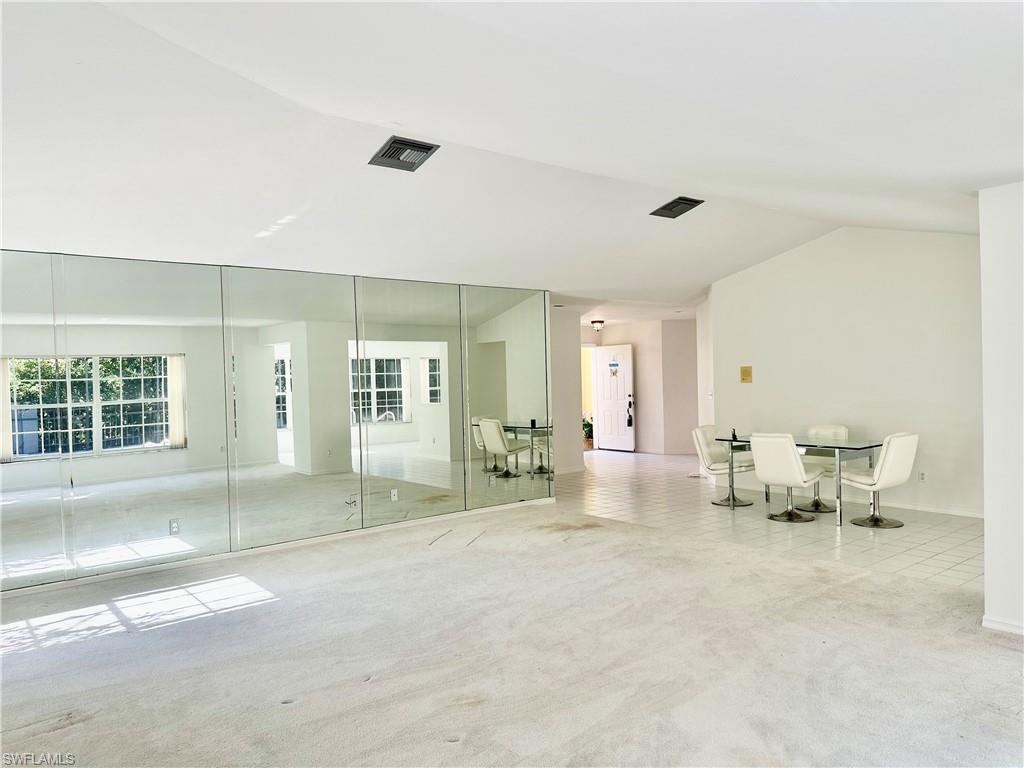 7010 Rue De Marquis Naples, FL 34108 - Photo 6 of 8 Unfurnished room featuring light carpet and vaulted ceiling