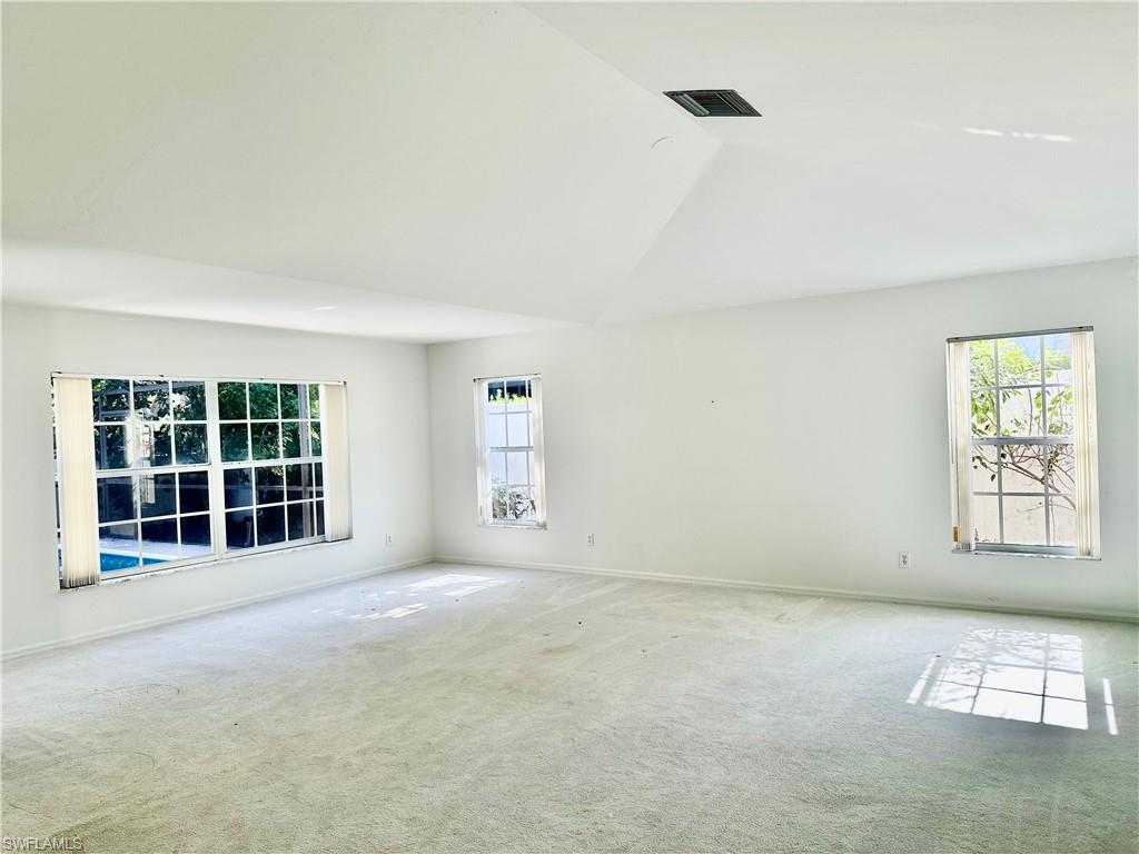 7010 Rue De Marquis Naples, FL 34108 - Photo 7 of 8 Carpeted spare room featuring vaulted ceiling and baseboards