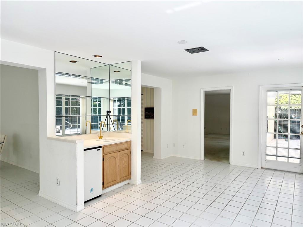 7010 Rue De Marquis Naples, FL 34108 - Photo 8 of 8 Bar area featuring light countertops, white dishwasher, light brown cabinetry, and healthy amount of natural light