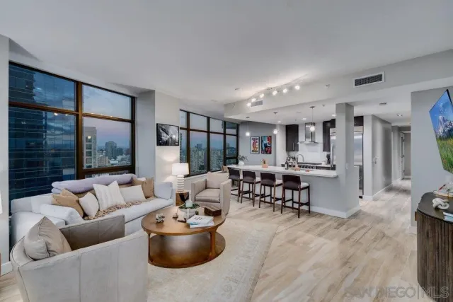 a large living room with stainless steel appliances kitchen island a large window in it