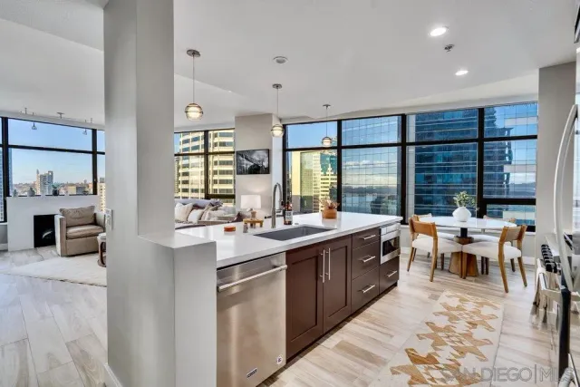 a room with stainless steel appliances a sink dishwasher a stove a dining table and chairs with wooden floor