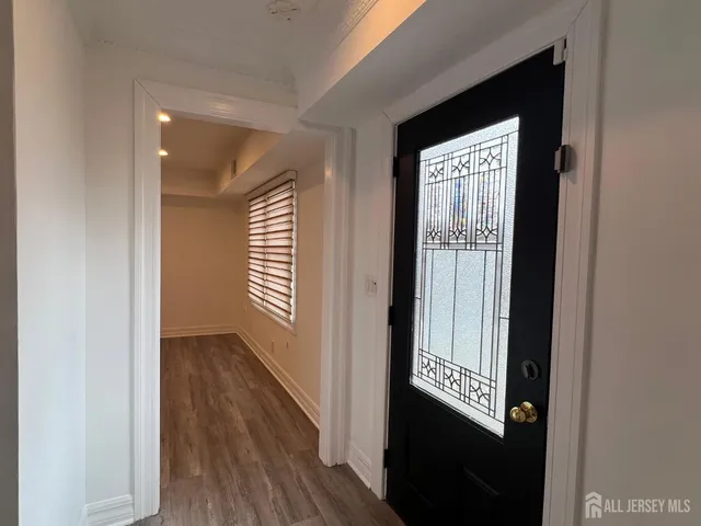 a view of a hallway with wooden floor and a bathroom