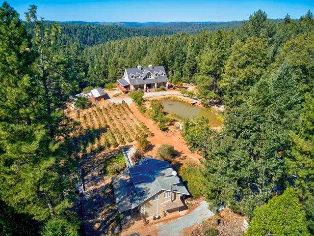 a view of a house with large tree and wooden fence