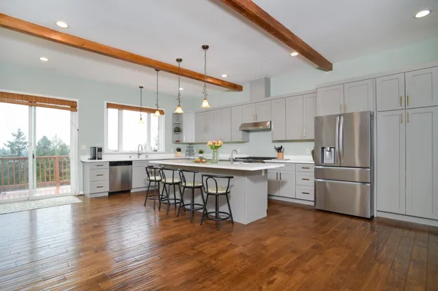 a kitchen with stainless steel appliances granite countertop a refrigerator a stove top oven a sink dishwasher and white cabinets with wooden floor