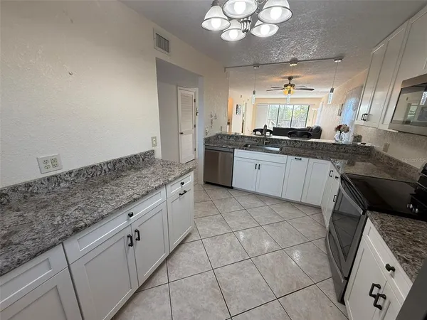 a kitchen with granite countertop white cabinets and stainless steel appliances