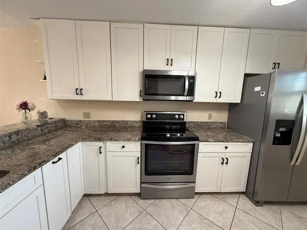 a kitchen with stainless steel appliances granite countertop a stove a refrigerator and a microwave