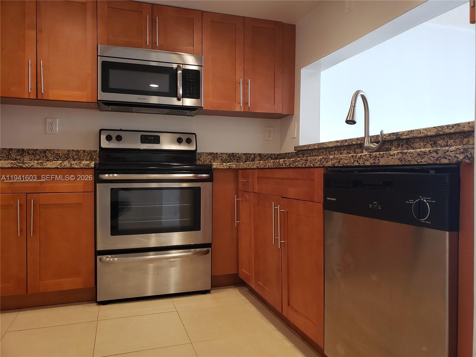 461 Southwest 113th Way, Unit 461 Pembroke Pines, FL 33025 - Photo 1 of 12 a kitchen with granite countertop a stove and a microwave