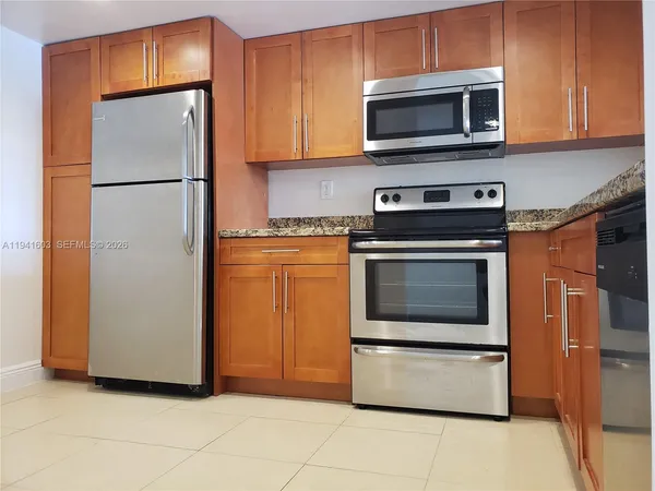 a kitchen with granite countertop a refrigerator and a stove top oven