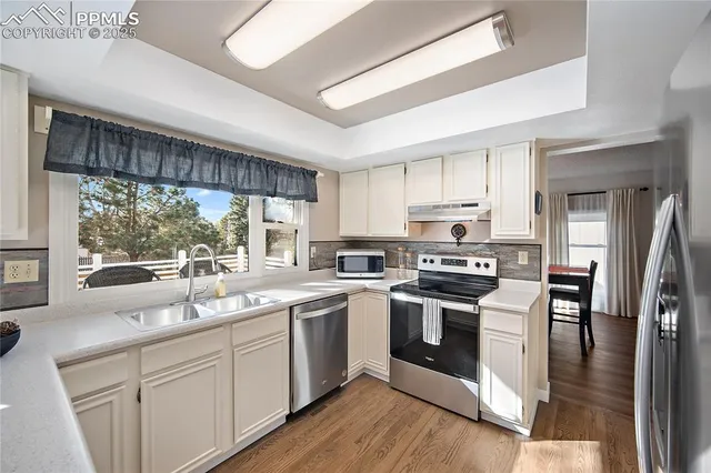 a kitchen with a sink stainless steel appliances cabinets and a large window