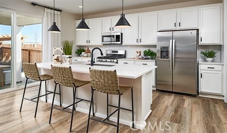 23863 Phoebe Drive Corona, CA 92883 - Photo 4 of 11 a kitchen with stainless steel appliances granite countertop a refrigerator a sink dishwasher a stove and white cabinets with wooden floor