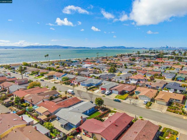an aerial view of a city with lots of residential buildings and ocean view in back