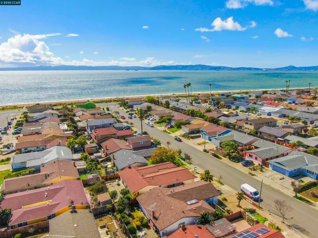 an aerial view of a city with lots of residential buildings and ocean view in back