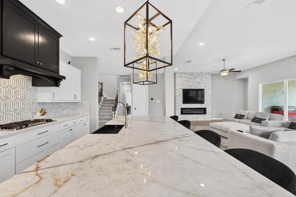 a kitchen with stainless steel appliances kitchen island granite countertop a stove top oven a sink dishwasher and white cabinets with wooden floor