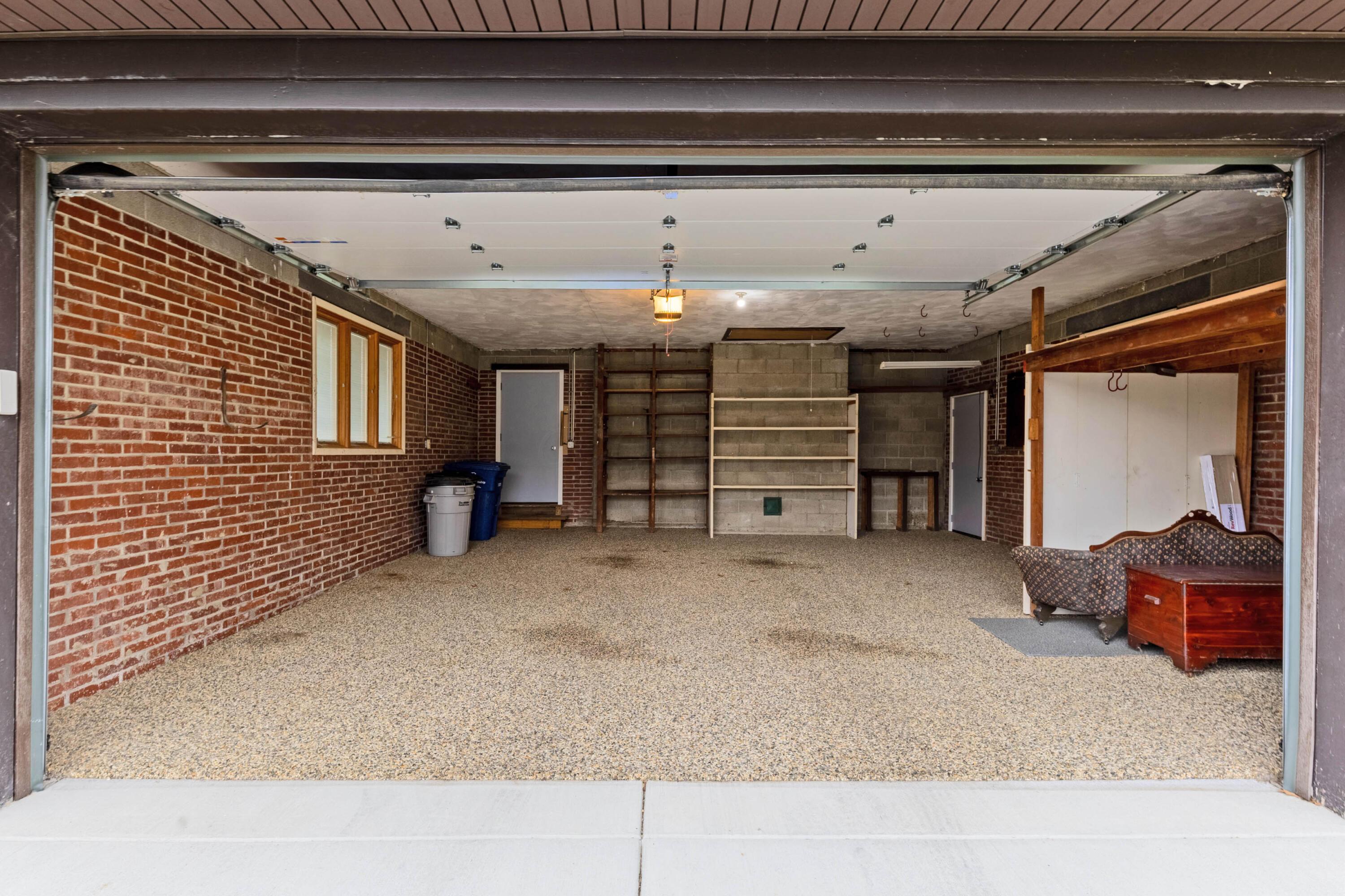 6982 Lee Road Westerville, OH 43081 - Photo 62 of 71 • 2+ car attached • Epoxy flooring • Pull-down attic access • Man door • Wall shelves • Brick walls • New Liftmaster® electric door opener ~ 2020 • New garage door ~ 2020