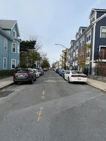 a city street lined with buildings and cars parked on the roadside