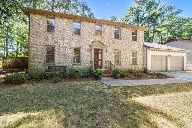 a view of a white house next to a yard with potted plants