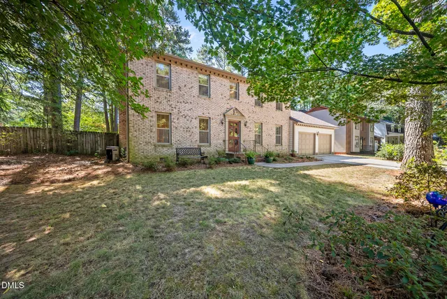 a front view of a house with a yard and trees