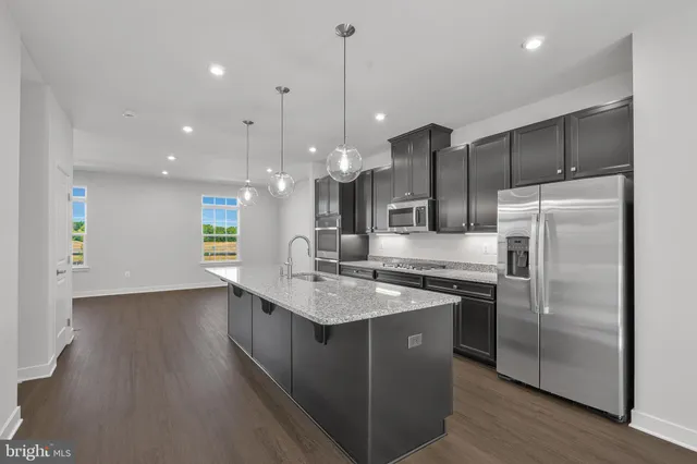 a kitchen with kitchen island a counter top space a sink appliances and cabinets