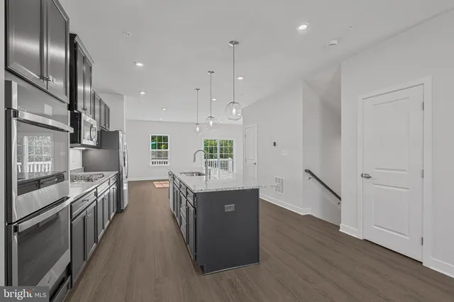 a kitchen with stainless steel appliances granite countertop a lot of counter space and wooden floors