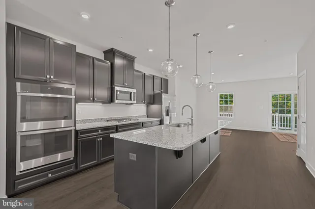 a kitchen with stainless steel appliances granite countertop a sink a stove and a refrigerator