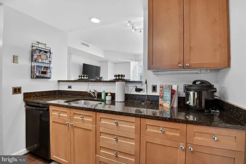 a kitchen with granite countertop a sink a stove and cabinets