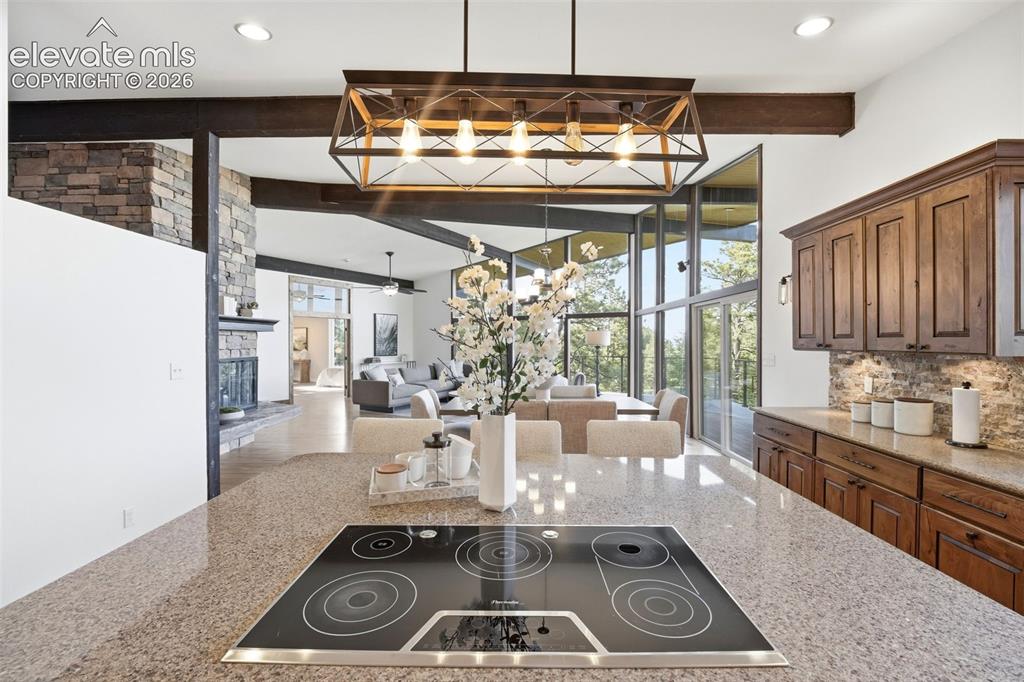 17 Pine Road Colorado Springs, CO 80906 - Photo 18 of 48 Kitchen island with an integrated cooktop, stone-finish countertop, and decorative pendant lighting