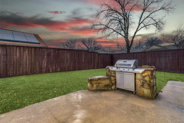 a view of backyard with barbeque grill and wooden fence