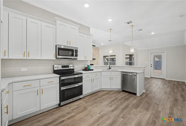 a kitchen with white cabinets and stainless steel appliances