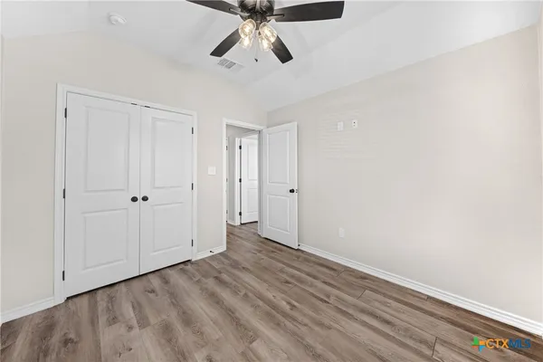 a view of empty room with wooden floor and ceiling fan