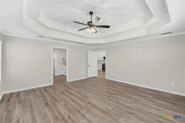 an empty room with wooden floor chandelier fan and windows