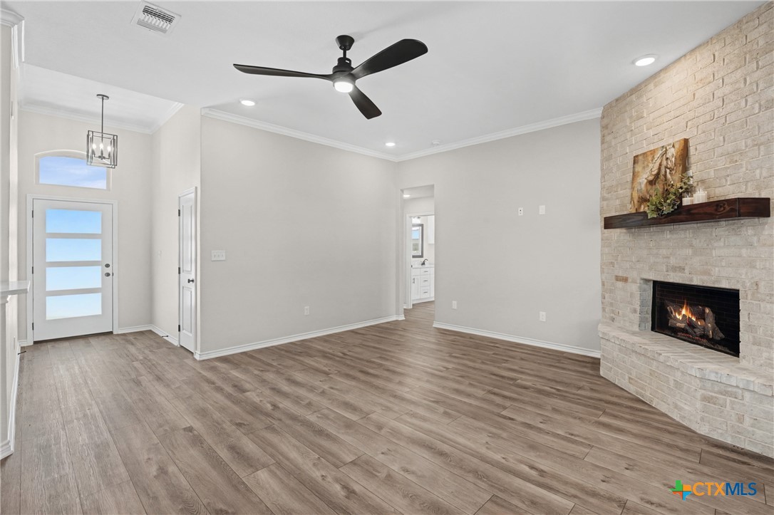 604 Magnolia Drive Troy, TX 76579 - Photo 6 of 33 a view of a livingroom with wooden floor a ceiling fan a fireplace and windows
