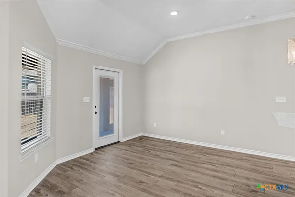 an empty room with wooden floor fireplace and windows